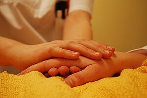 Eine Hand hält eine Hand einer liegenden Person